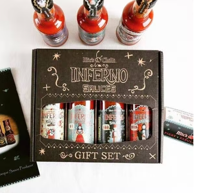Coffret cadeau de sauces piquantes Inferno de Mic's Chilli avec emballage décoratif et bouteilles colorées.